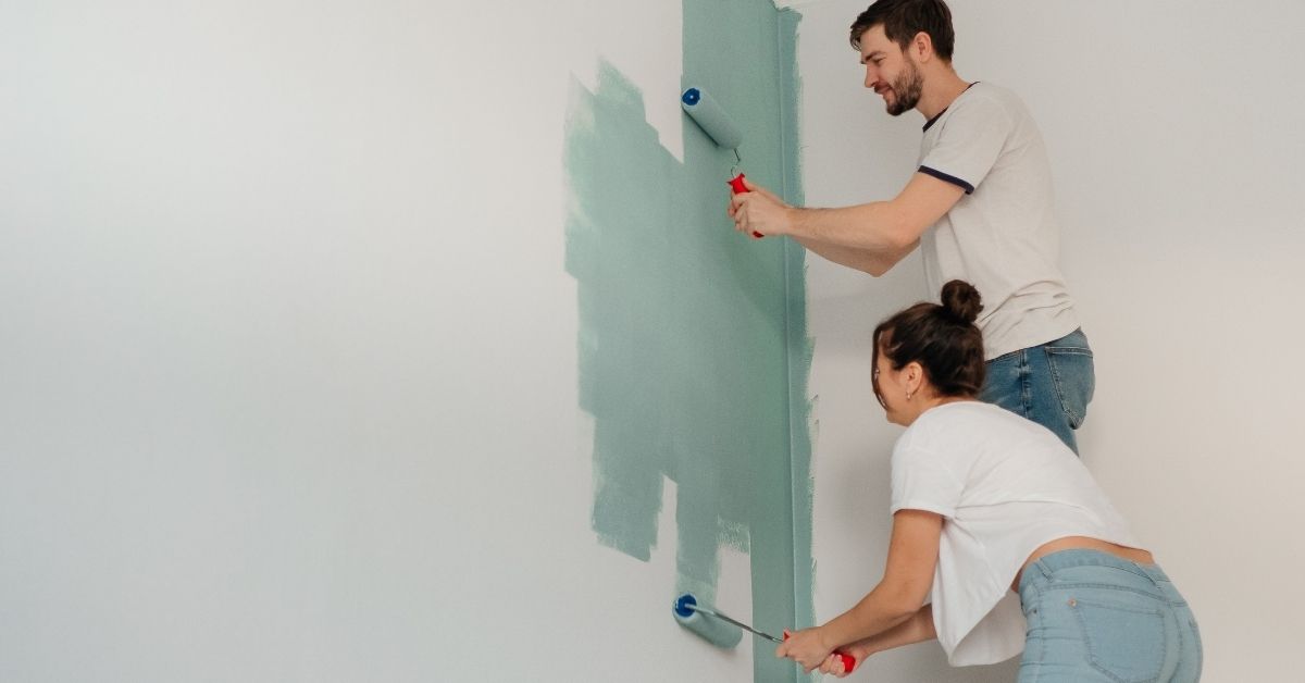 A young couple painting a wall in their home in Scottsdale an aqua-green color