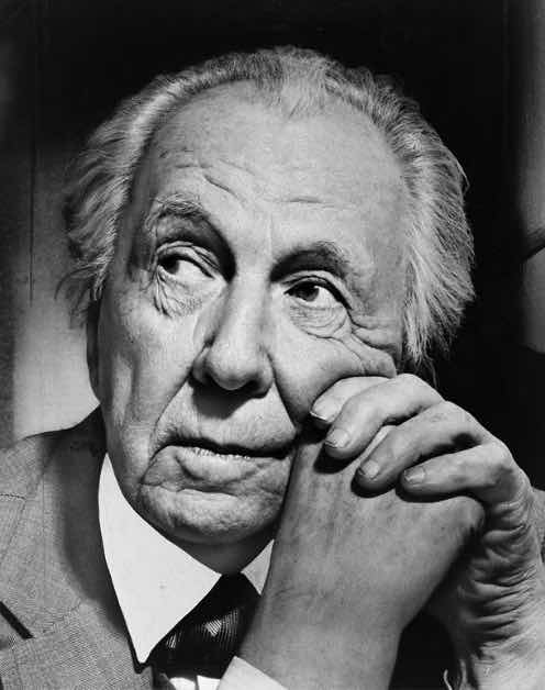 A photo of Frank Lloyd Wright resting his chin on folded hands