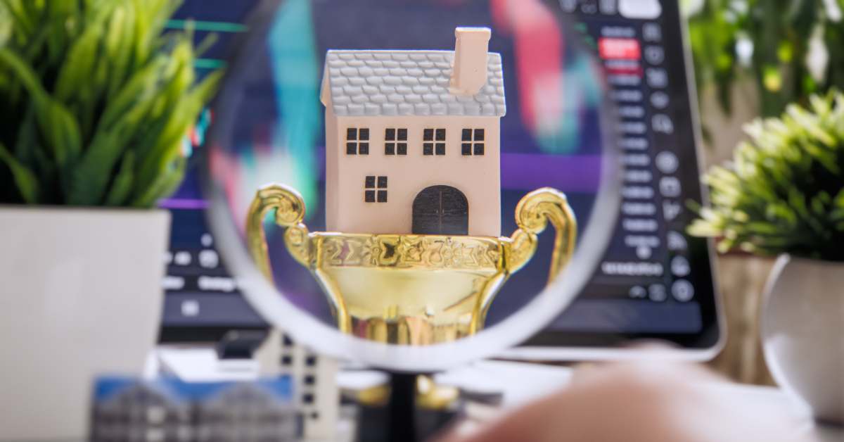 A little Scottsdale home set in a gold trophy in front of a laptop