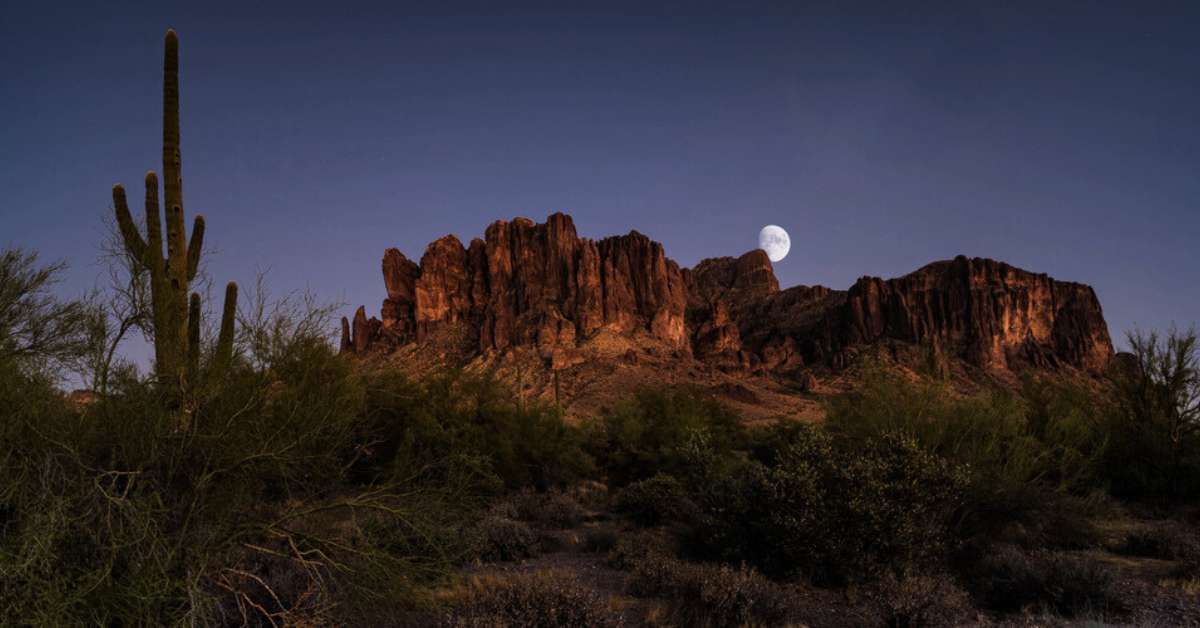 Superstition Mountains at night with the moon above.