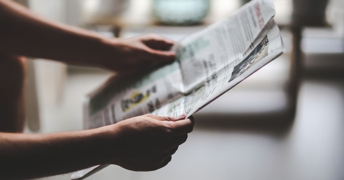 A man's arms holding a newspaper