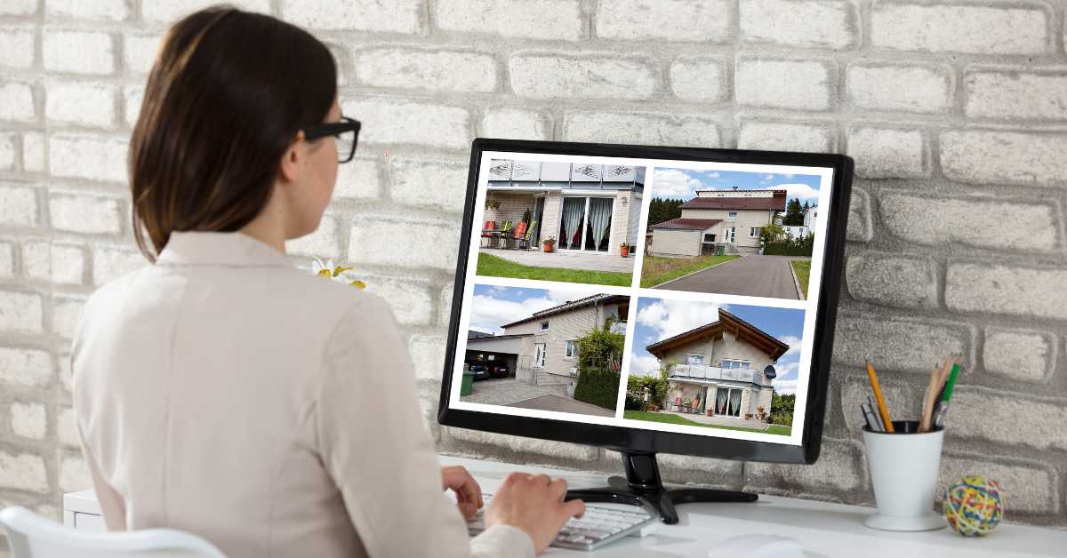 A woman viewing a Scottsdale home on her computer monitor mounted on a desk against a brick wall