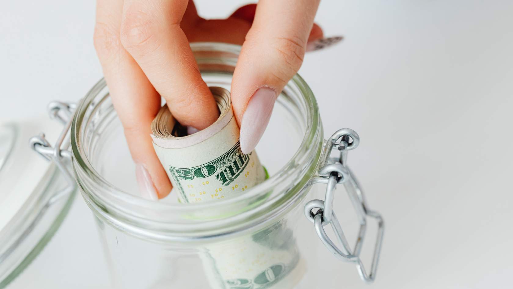 A woman putting a roll of bills inside a money jar as savings towards her Scottsdale home purchase