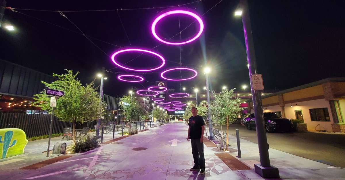 A man standing under purple lights going to the parking garage of downtown Gilbert at night