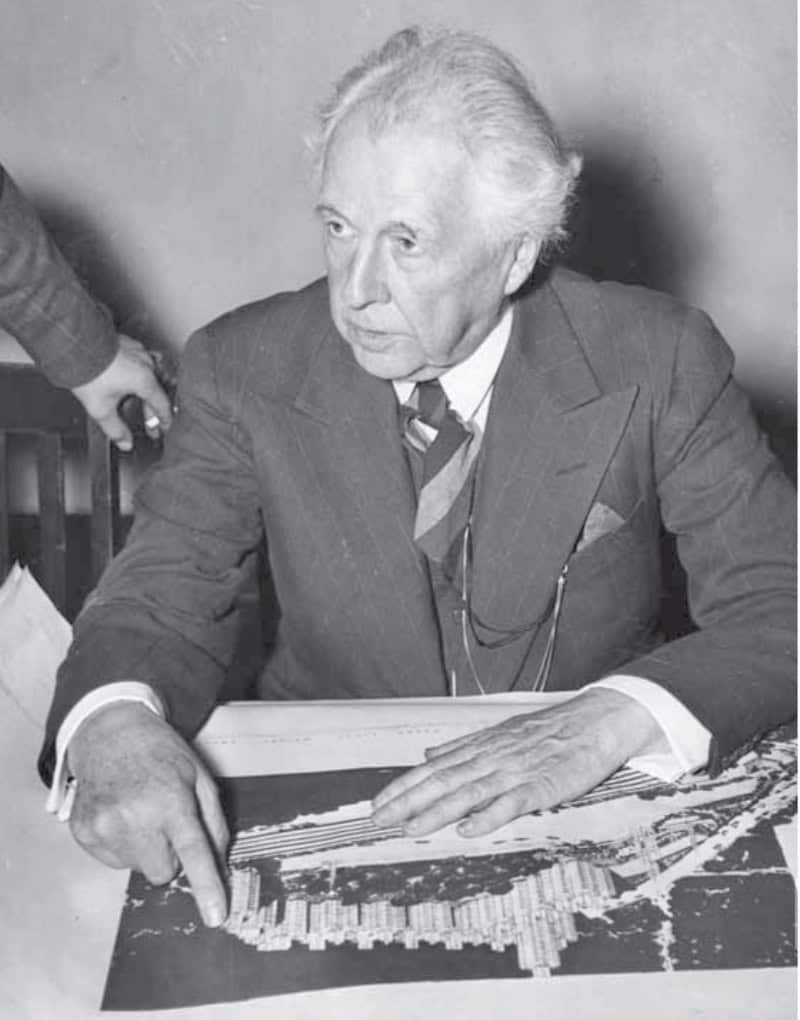 Frank Lloyd Wright sitting at a table with paperwork