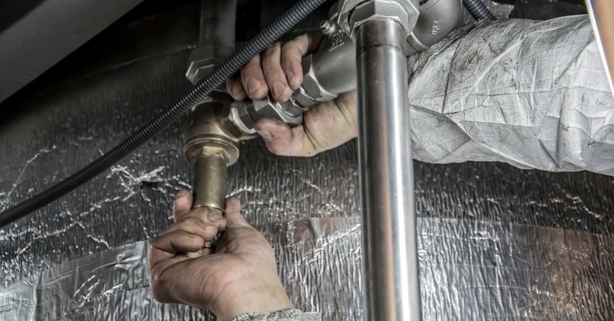 A plumber working on pipes in a Scottsdale home for sale