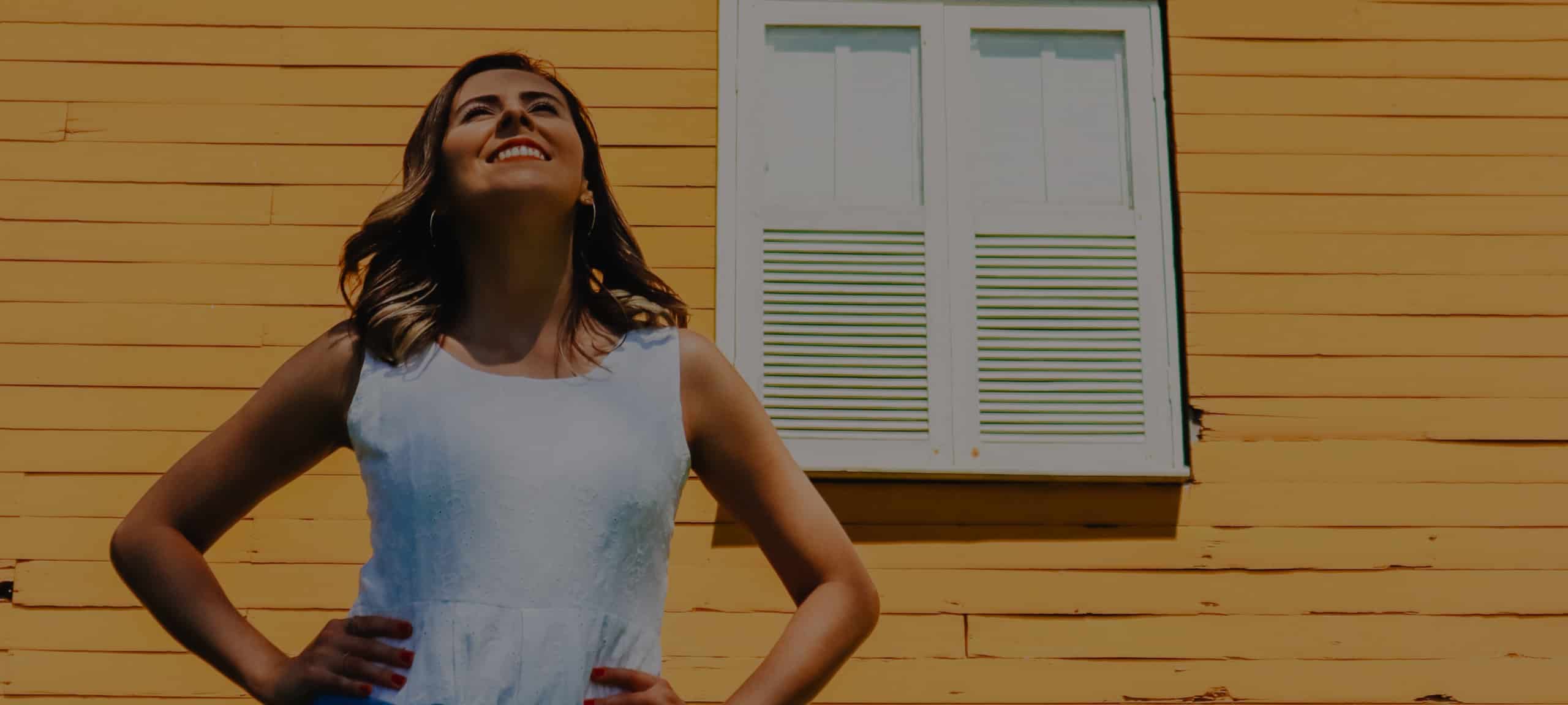 A young female home buyer standing in front of the shutters of her new Scottsdale home.